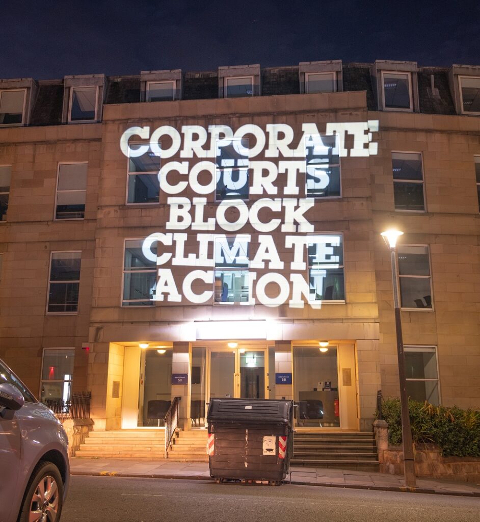 Projection of words 'corporate courts block climate action' on to the offices of law firm Clyde & Co in Edinburgh